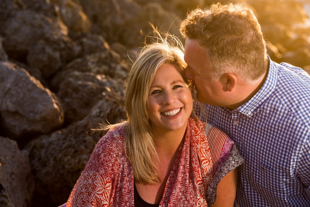 couple smiling on rocks at sunset