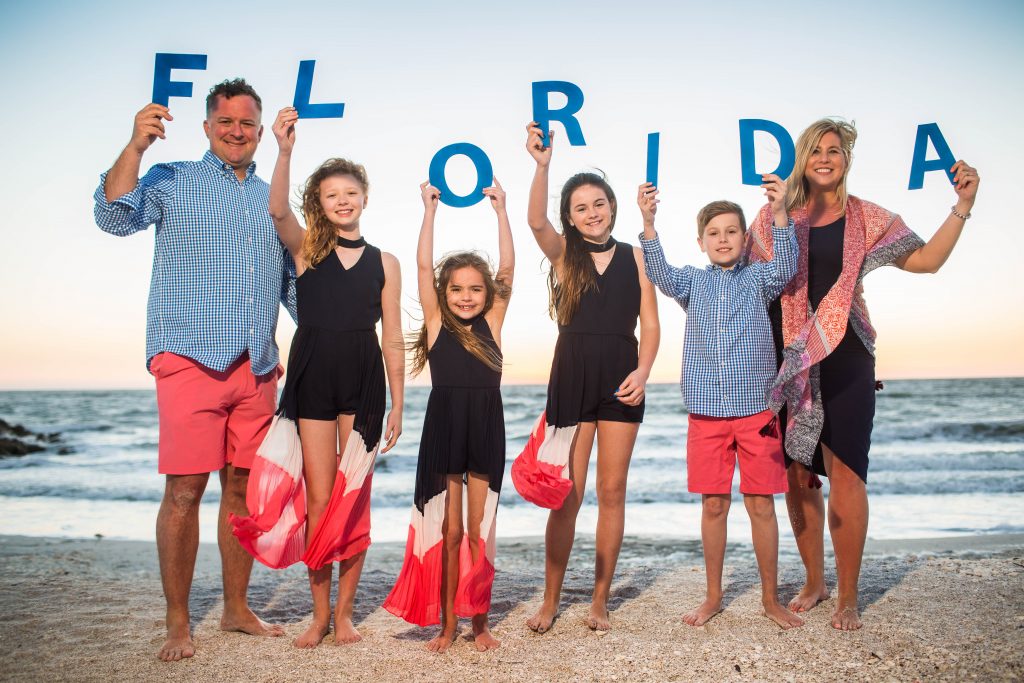family on the beach holding up letters that spell out FLORIDA